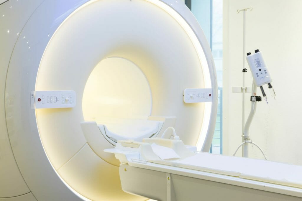 Weißer Magnetresonanztomograph in beleuchtetem Zimmer in Klinik